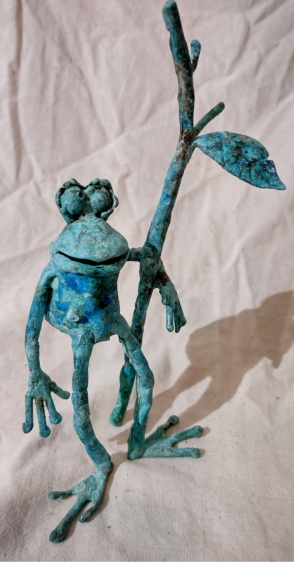 Copper froglette figurine. Standing, holding onto a branch.