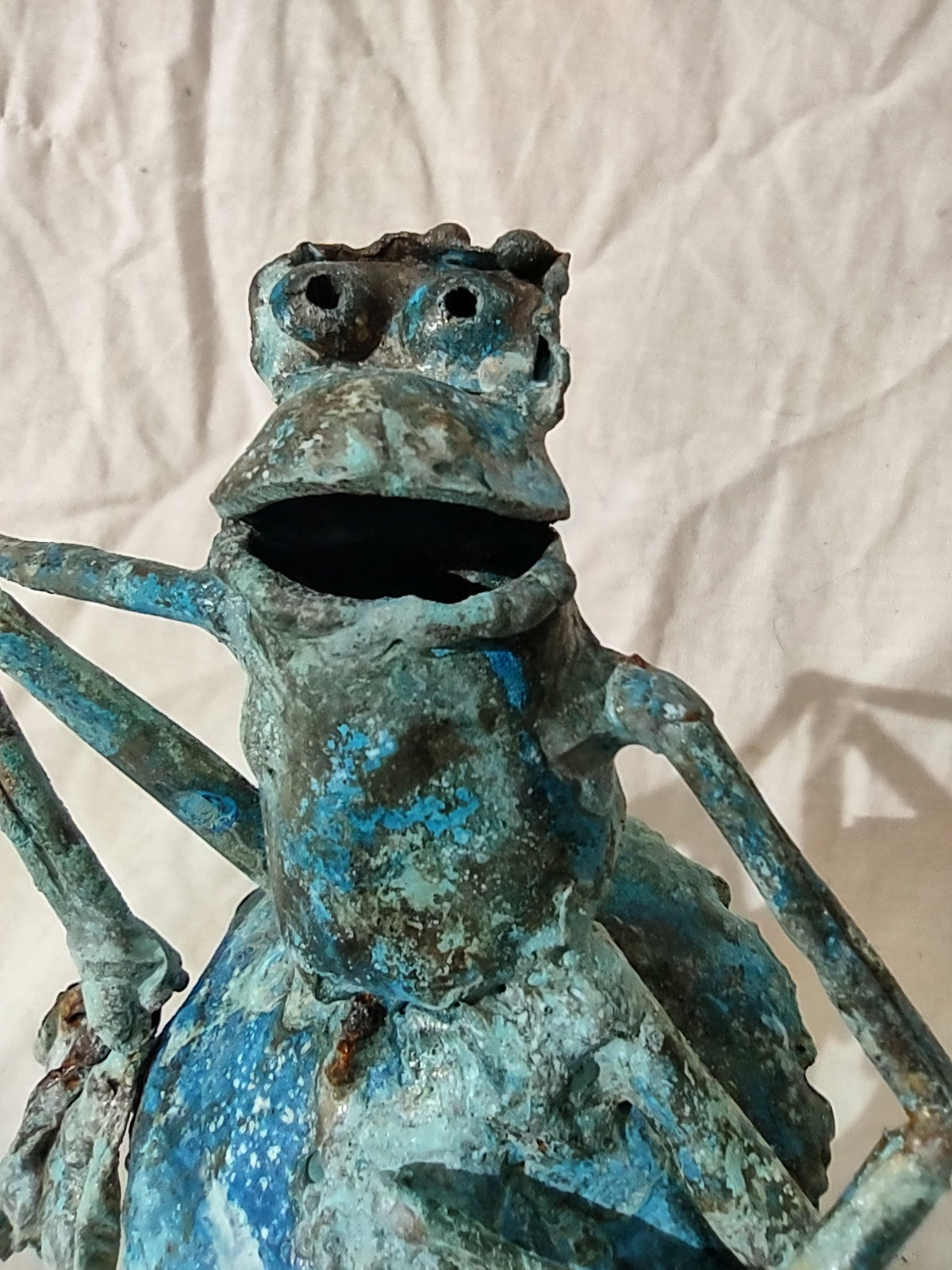 Copper froglette figurine sitting on a mushroom in a mushroom patch.