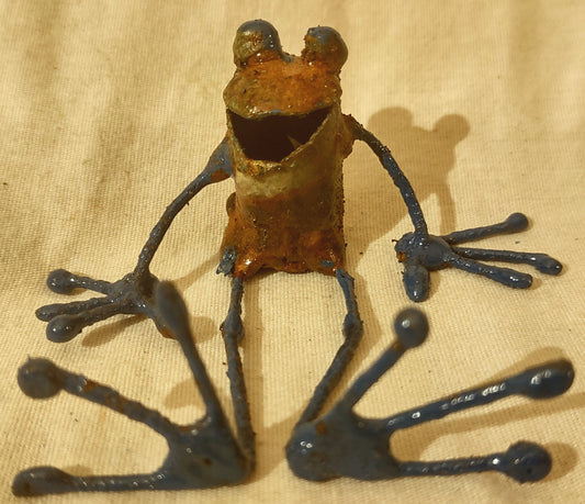 Tiny copper frog seated legs stretched out.